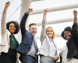 Four happy people with raised fists