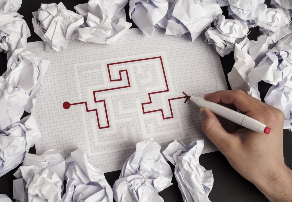 Hand working through a paper maze